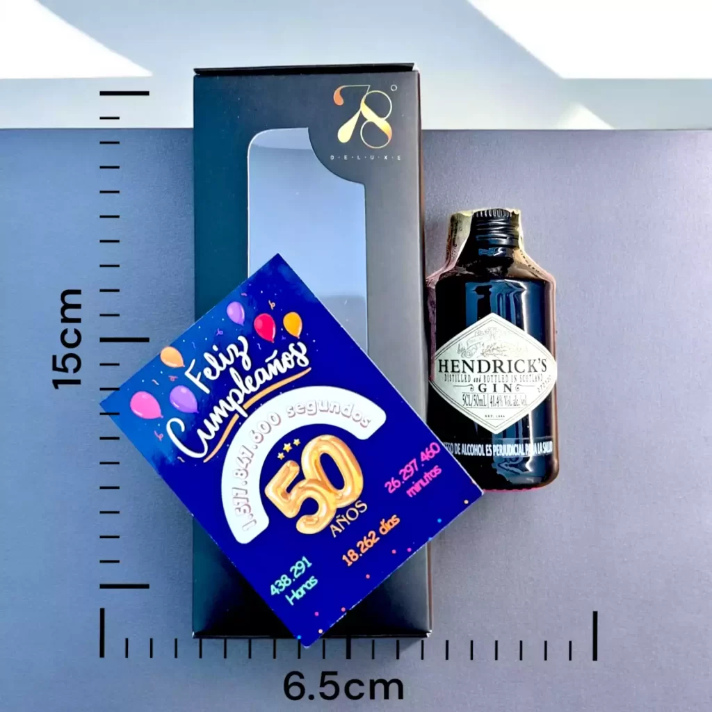 La Mini Botella de Ginebra Hendrick’s 50ml es la versión en miniatura de una de las ginebras más exclusivas y distintivas del mundo. Elaborada en Escocia, esta ginebra premium destaca por su innovador proceso de destilación en pequeños lotes y su infusión única de pepino y pétalos de rosa, lo que le otorga un perfil de sabor fresco y floral. Su presentación en una icónica botella negra y su sabor refinado la han convertido en una de las ginebras más apreciadas por los amantes de los destilados de calidad. En 78 Grados Deluxe, ofrecemos esta mini botella con una caja premium individual y una tarjeta impresa personalizada, asegurando un detalle exclusivo y elegante, ideal para obsequios especiales.